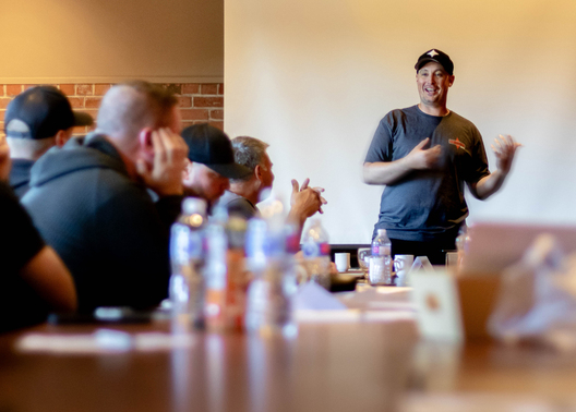 Aaron Jones, Président et chef de la direction de Kraun Electric, discute avec un groupe de personnes autour d'une table.