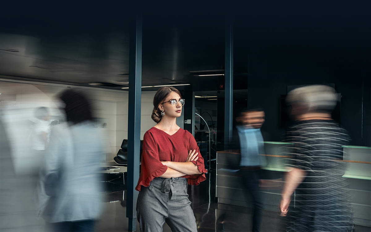 Femme d'affaires debout pendant que les gens se dépêchent autour d'elle