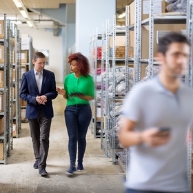 Woman in green shirt walking in storeroom with her business advisor.